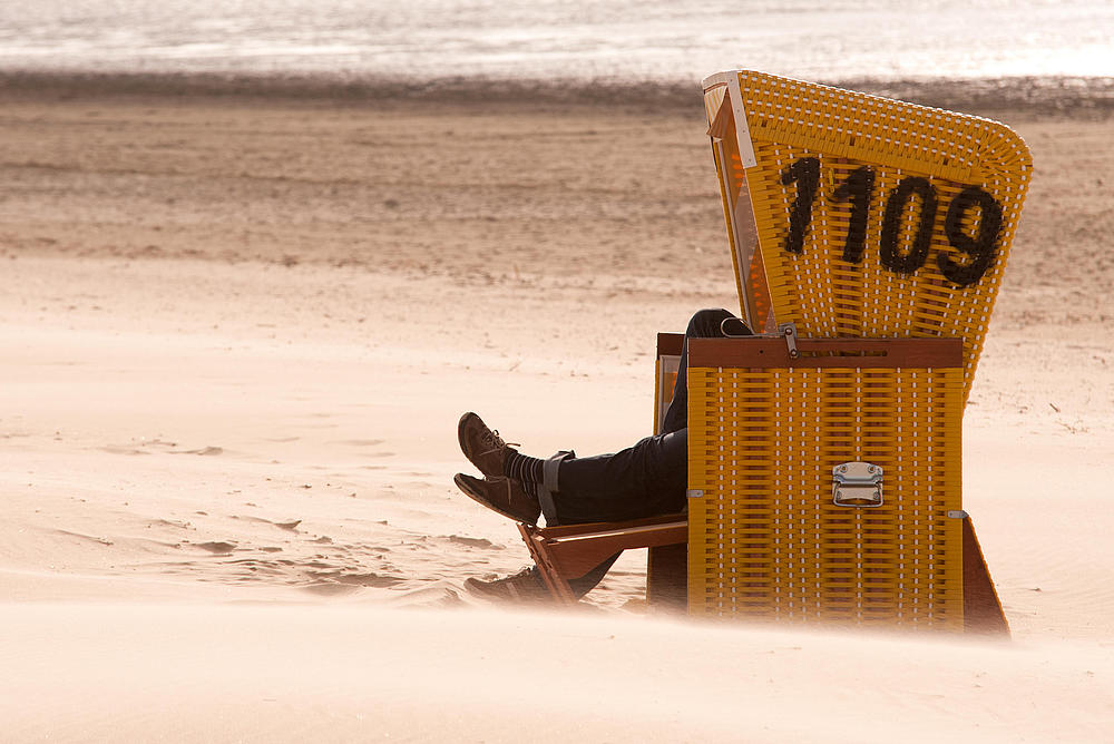 A beach chair with two people inside, with the sea in the background