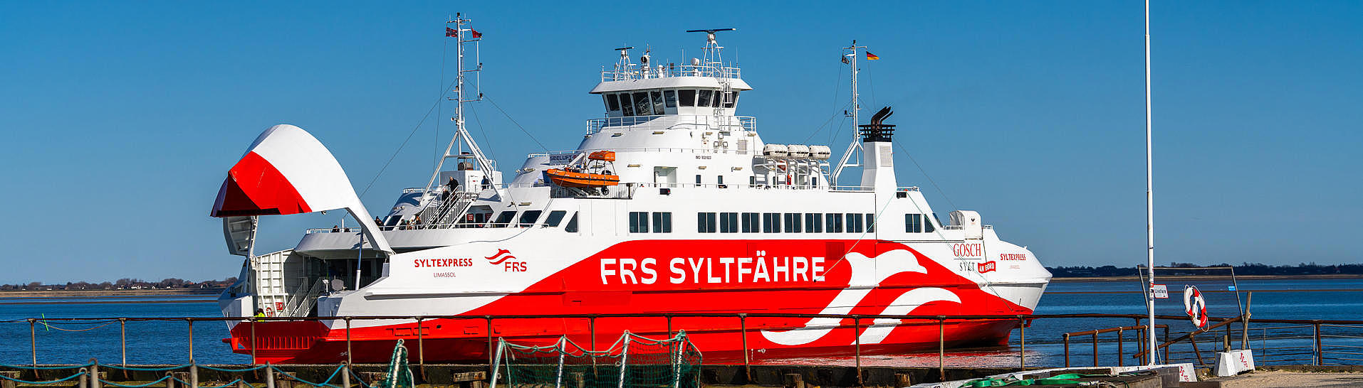 The Sylt ferry under a bright blue sky at the harbor entrance. 