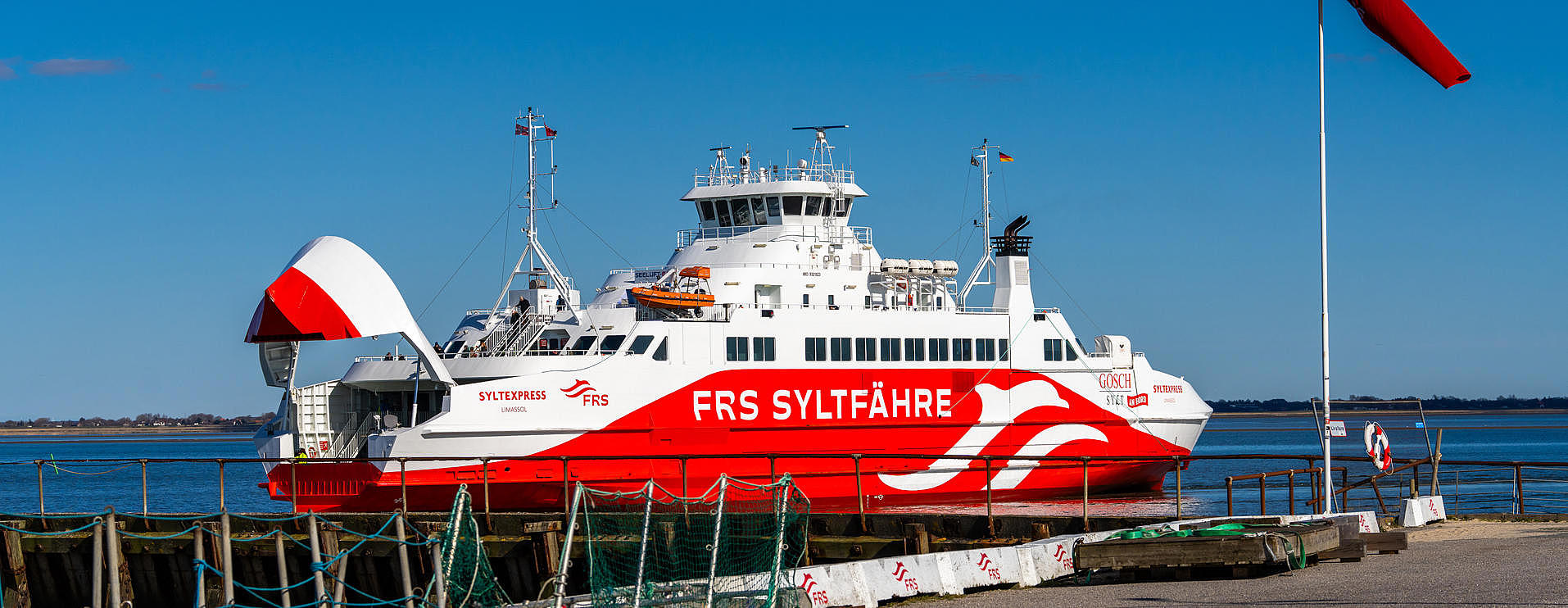 The Sylt ferry under a bright blue sky at the harbor entrance. 