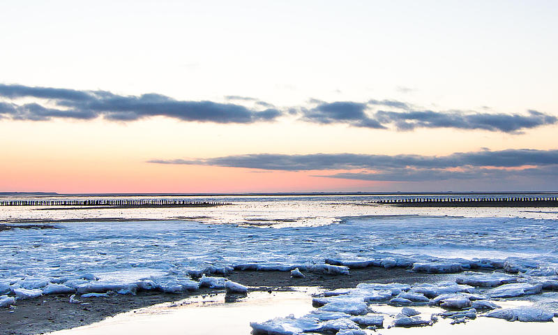 The Wadden Sea in winter during low tide, covered in snow and ice.