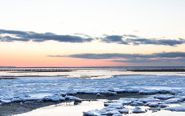 The Wadden Sea in winter during low tide, covered in snow and ice.
