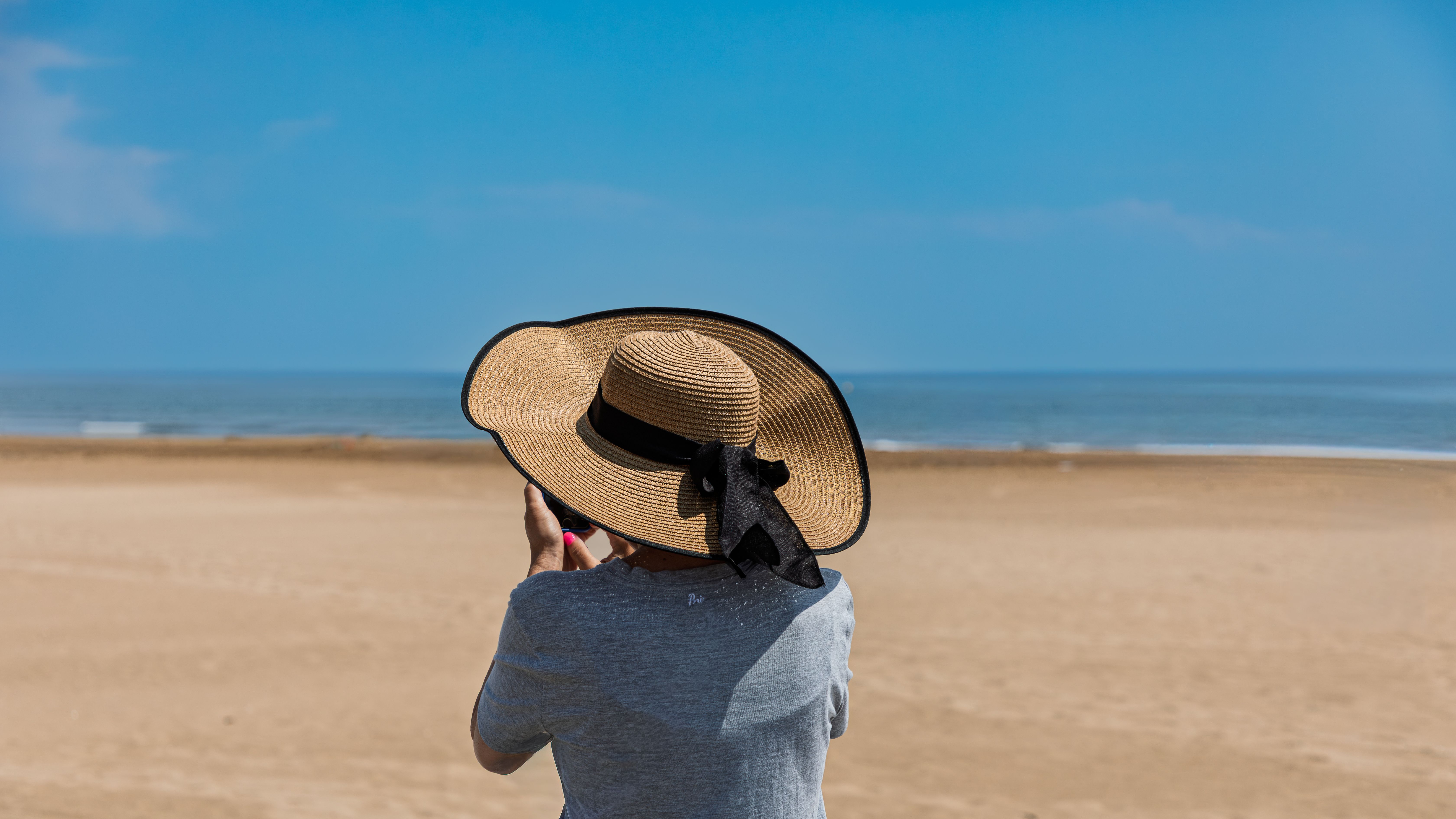 Eine Frau mit Strohhut fängt die idyllische Strandkulisse ein