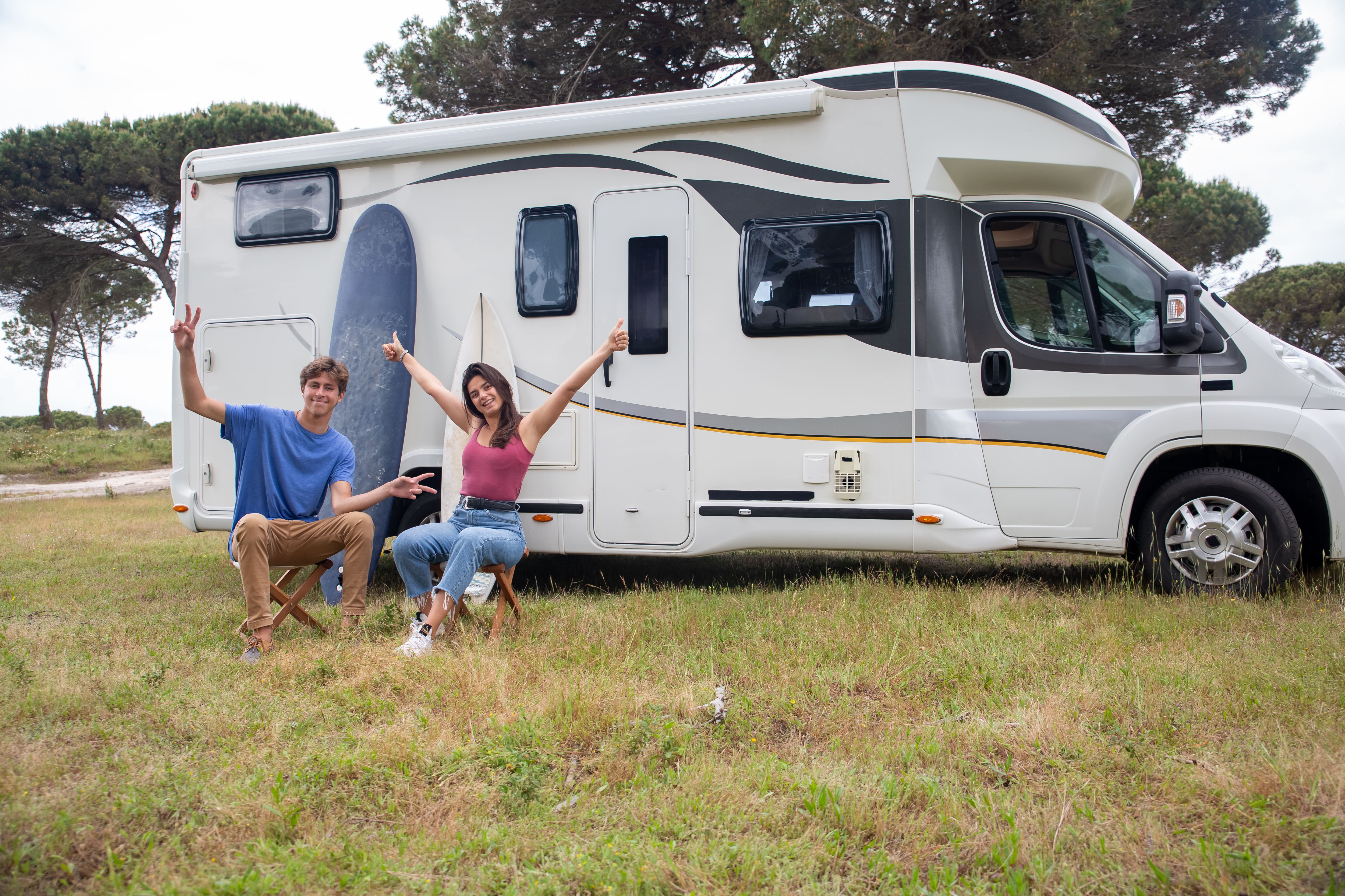 Glückliches Paar entspannt sich neben dem Camper an einem sonnigen Campingplatz