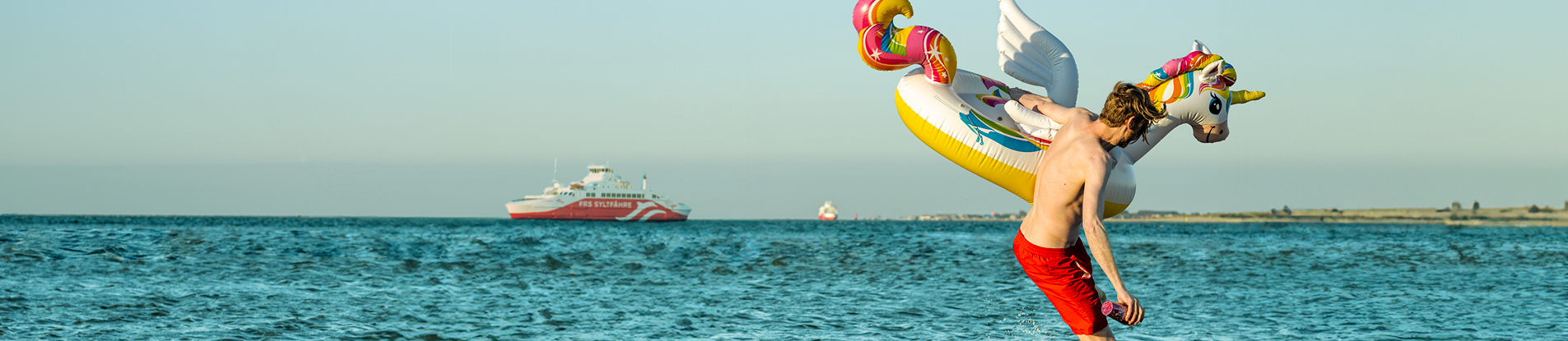 Mann mit Einhorn beim BAden mit SyltExpress
